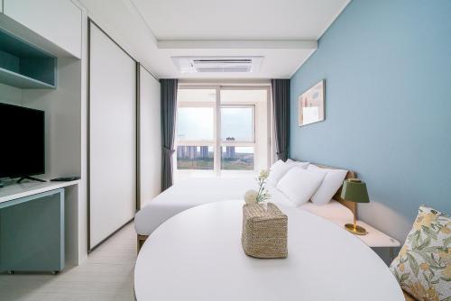 a room with a bed and a table and a tv at Urbanstay Songdo Moonlight Park in Incheon