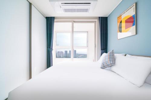 a bedroom with a white bed and a window at Urbanstay Songdo Moonlight Park in Incheon