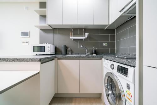 a white kitchen with a washer and dryer at Urbanstay Songdo Moonlight Park in Incheon