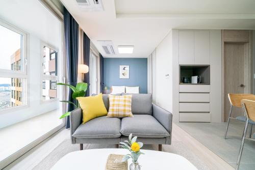 a living room with a gray couch and yellow pillows at Urbanstay Songdo Moonlight Park in Incheon