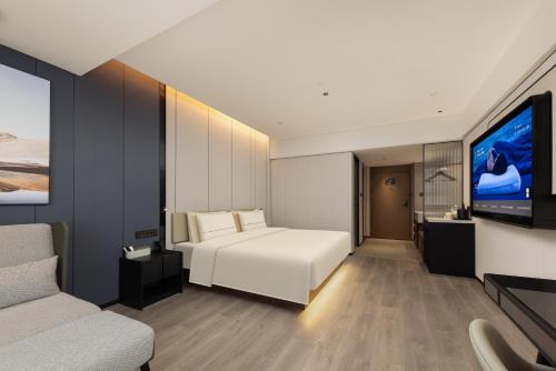 a bedroom with a white bed and a flat screen tv at Atour Hotel Guangzhou Railway Station University of Chinese Medicine - Complimentary Self-Service Laundry in Guangzhou