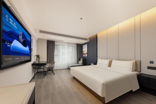 a bedroom with a large white bed and a tv at Atour Hotel Guangzhou Railway Station University of Chinese Medicine - Complimentary Self-Service Laundry in Guangzhou