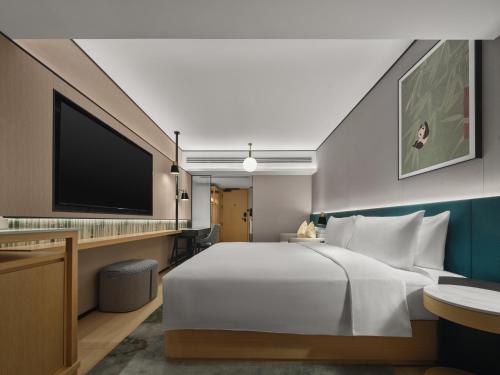 a hotel room with a bed and a flat screen tv at Hilton Garden Inn Chengdu Tianfu Panda Tower in Chengdu