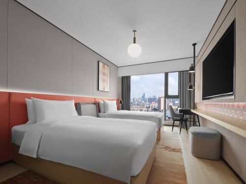 two beds in a hotel room with a large window at Hilton Garden Inn Chengdu Tianfu Panda Tower in Chengdu