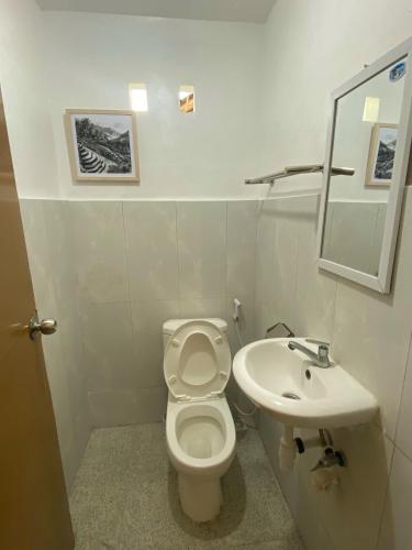 a white bathroom with a toilet and a sink at NOMAD Tropical Hotel Canggu in Dalung