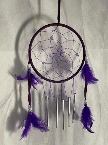 a dream catcher with purple feathers hanging on a wall at nuitzen in Boyer