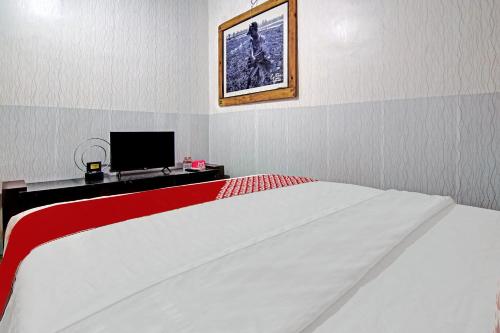 a bedroom with a red and white bed and a monitor at Hotel O Poris Residence Syariah in Porisgaga