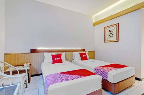 two beds in a room with a table and a chair at Collection O Riau Near Trans Studio Bandung Formerly Asteria Hotel in Bandung