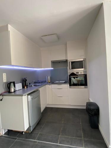 Elle comprend une petite cuisine avec des placards blancs et des murs bleus. dans l'établissement Le Cap d Agde, au Cap d'Agde