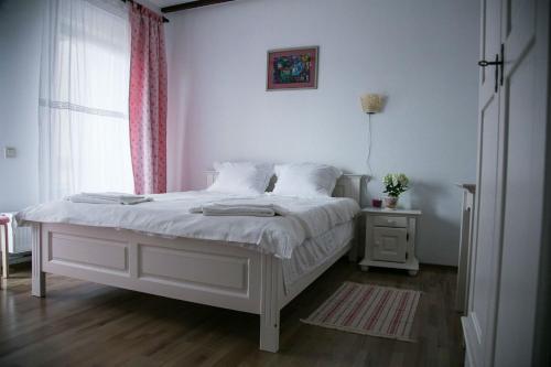 um quarto com uma cama branca e uma janela em Pensiunea Margareta em Budeasa Mică