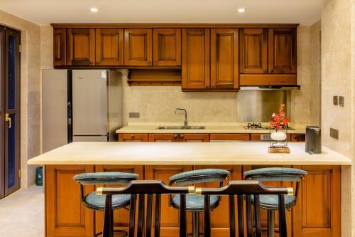 a kitchen with wooden cabinets and a island with bar stools at 福湾海涛 in Sanya