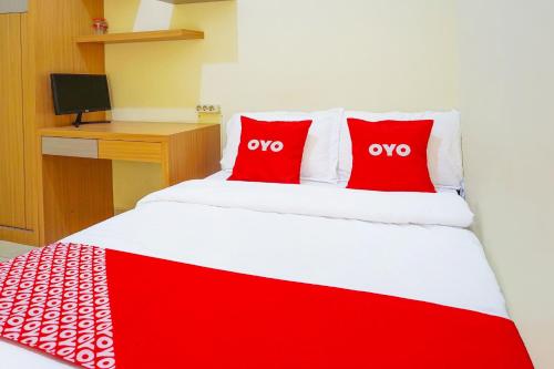 a red and white bed with two red pillows on it at Flagship 90723 Berlima Guest House Syariah in Malang