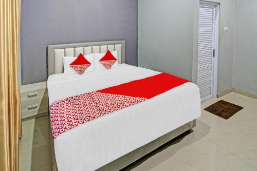 a bedroom with a white and red bed with red pillows at Hotel O Gm Guest House in Wonogiri