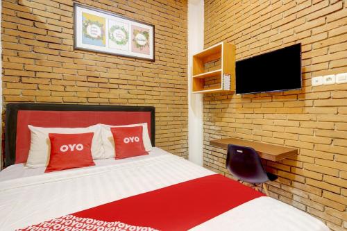 a bedroom with a bed and a tv on a brick wall at Hotel O D Kost In Kandri Semarang in Semarang