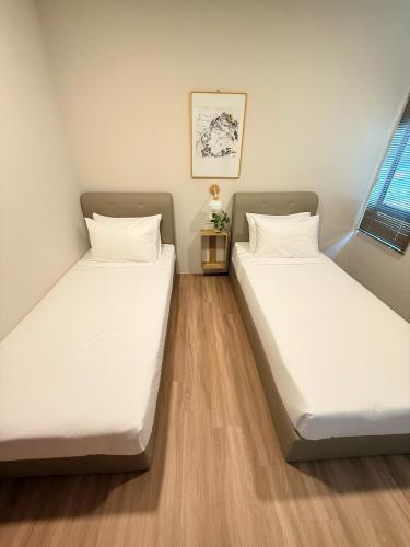 two beds in a room with white sheets at TwinTree Kelawai in George Town