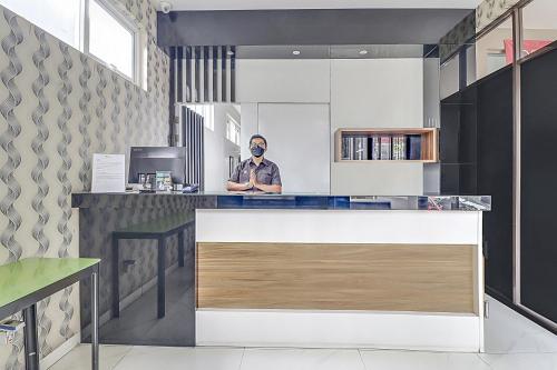 a man is standing at a counter in a kitchen at Collection O Cihampelas Near Ciwalk Formerly Regia Cihampelas in Bandung