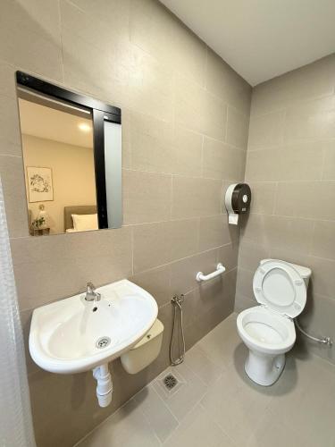 a bathroom with a sink and a toilet and a mirror at TwinTree Kelawai in George Town