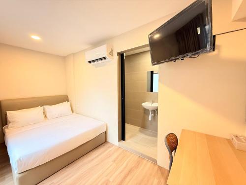 a small room with a bed and a television on the wall at TwinTree Kelawai in George Town