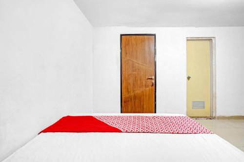 a bedroom with a red and white bed with a door at OYO Life 90791 Royale Margorejo in Wonocolo