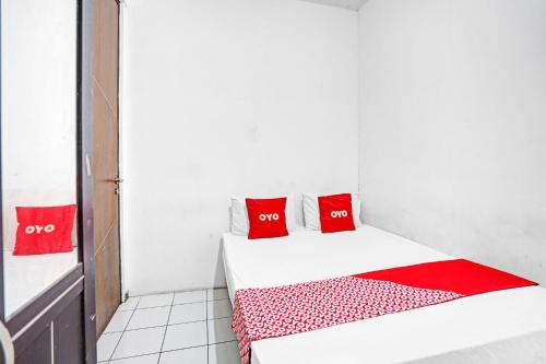 a small bedroom with red pillows on a bed at OYO Life 90791 Royale Margorejo in Wonocolo