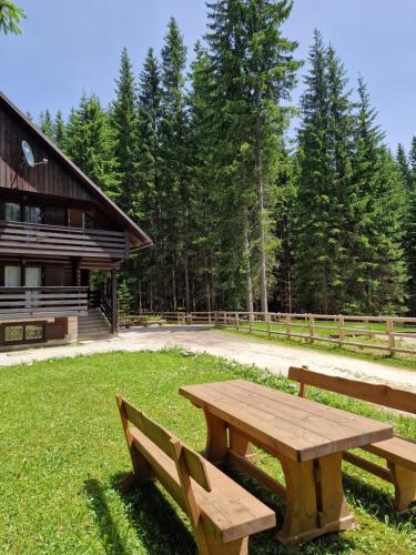 einem hölzernen Picknicktisch im Gras neben einer Hütte in der Unterkunft Forest Apartments POKLJUKA in Zgornje Gorje