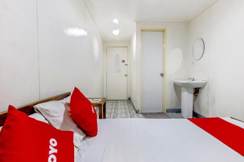 a bedroom with a bed with red pillows and a sink at Metro Deluxe Residences in Manila