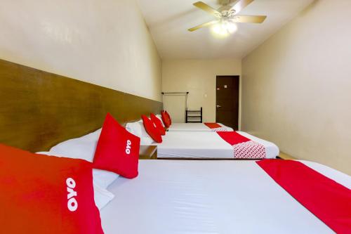 two beds in a bedroom with red and white pillows at Metro Deluxe Residences in Manila