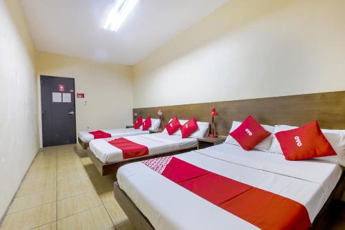 three beds in a room with red pillows on them at Metro Deluxe Residences in Manila