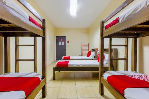 a room with three bunk beds with red and white sheets at Metro Deluxe Residences in Manila