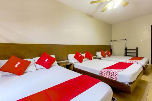 a room with three beds with red and white pillows at Metro Deluxe Residences in Manila