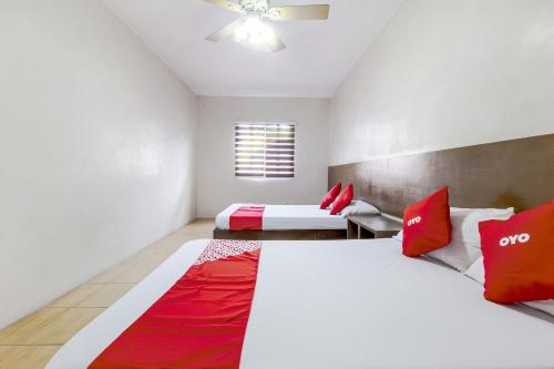 two beds in a room with red and white pillows at Metro Deluxe Residences in Manila