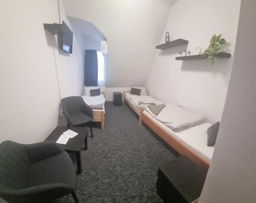 a room with two beds and chairs in a room at Romantik Étterem - Panzió in Tatabánya