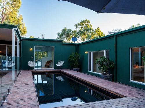 a green house with a swimming pool and a deck at Signature Accommodation Montez House Pool Retreat in Castlemaine