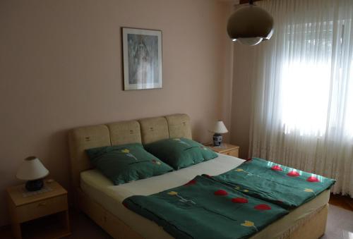 a bed with green sheets and red decorations on it at Bibinje Apartment in Bibinje
