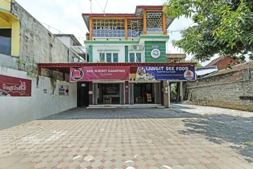 a building with a sign in front of a street at Hotel O Dangau Datuk Guesthouse in Ngabean