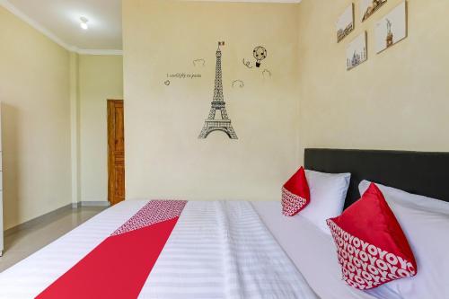 a bedroom with a bed with red pillows and the eiffel tower at Hotel O Dangau Datuk Guesthouse in Ngabean