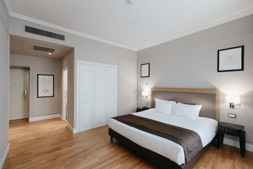 a bedroom with a large white bed and wooden floors at Grand Hotel Yerevan - Small Luxury Hotels of the World in Yerevan