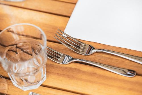 two forks and a glass on a wooden table at TREMONDI - Boutique BnB in Quarten