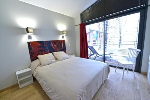 a bedroom with a large bed and a large window at Résidence le Clos des Chênes in Le Massegros