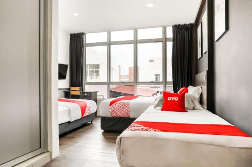 a bedroom with two beds with red and white sheets at Hotel O Kl2f Rest & Go in Shah Alam