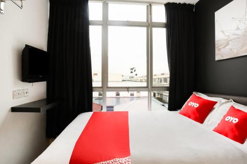 a bedroom with a bed with red pillows and a window at Hotel O Kl2f Rest & Go in Shah Alam