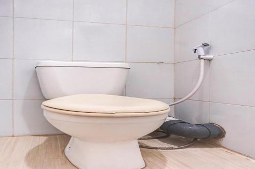 a white toilet in a bathroom with a hose at OYO 90949 Apartement Cibubur Village Kaisar Property in Depok