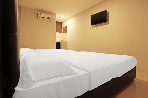 a bedroom with a white bed with a tv on the wall at Hotel O Marina World in Kuching