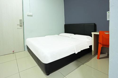 a bedroom with a bed with white sheets and a desk at Hotel O Marina World in Kuching