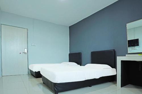 a bedroom with two beds and a tv on a wall at Hotel O Marina World in Kuching