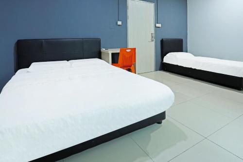 a bedroom with two beds and a orange chair at Hotel O Marina World in Kuching