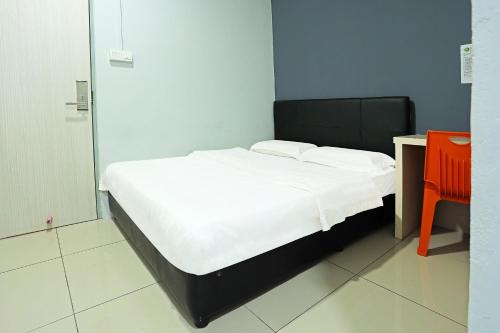 a bedroom with a bed with white sheets and a desk at Hotel O Marina World in Kuching