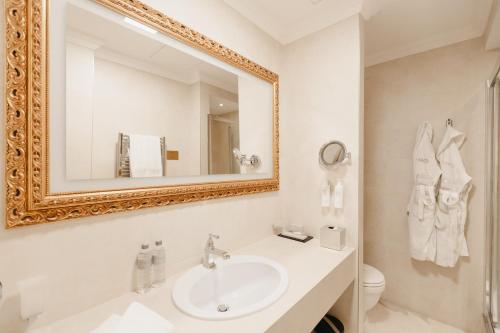 a white bathroom with a sink and a mirror at Grand Hotel Yerevan - Small Luxury Hotels of the World in Yerevan