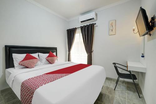 a bedroom with a bed with red pillows and a window at Capital O 90983 Harmony Easy Stay in Yogyakarta