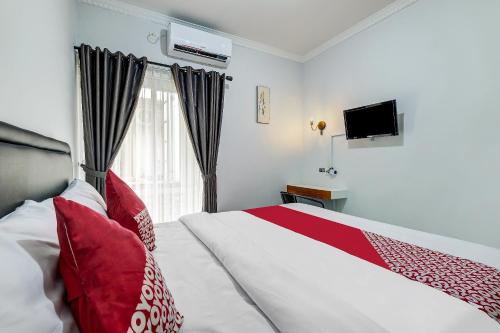a bedroom with a bed with red pillows and a window at Capital O 90983 Harmony Easy Stay in Yogyakarta